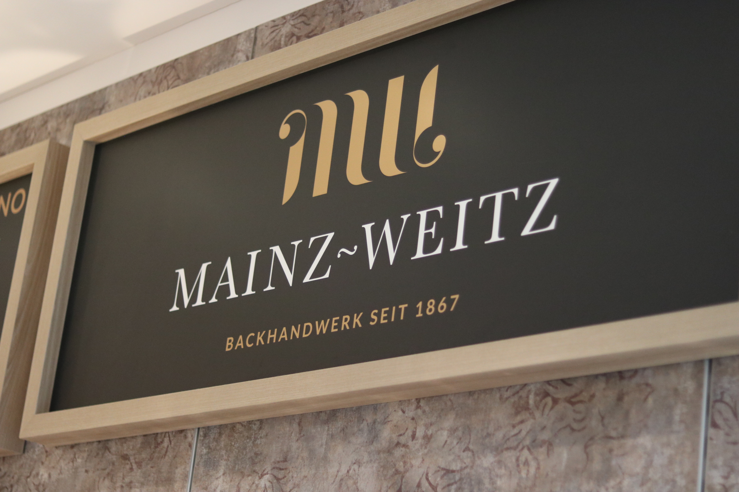 Wandtafel mit Logo der Bäckerei Mainz-Weitz in Jülich, geführt von Patrick Weitz – geprüfter Brotsommelier mit Herz für Handwerk